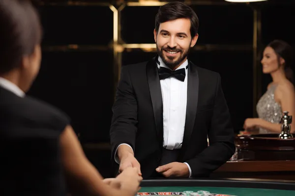 সবুজ বিলাসবহুল গাউন পরা এক নারী অলংকৃত রুলেট চাকার পাশে—যা 4777BET1–এর উচ্চমানের ক্যাসিনো পরিবেশকে প্রকাশ করে।